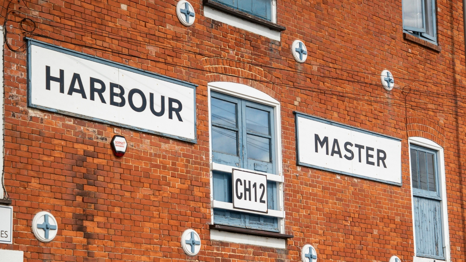 Harbour Master signs on a red brick harbour building, beside a window marked CH12.